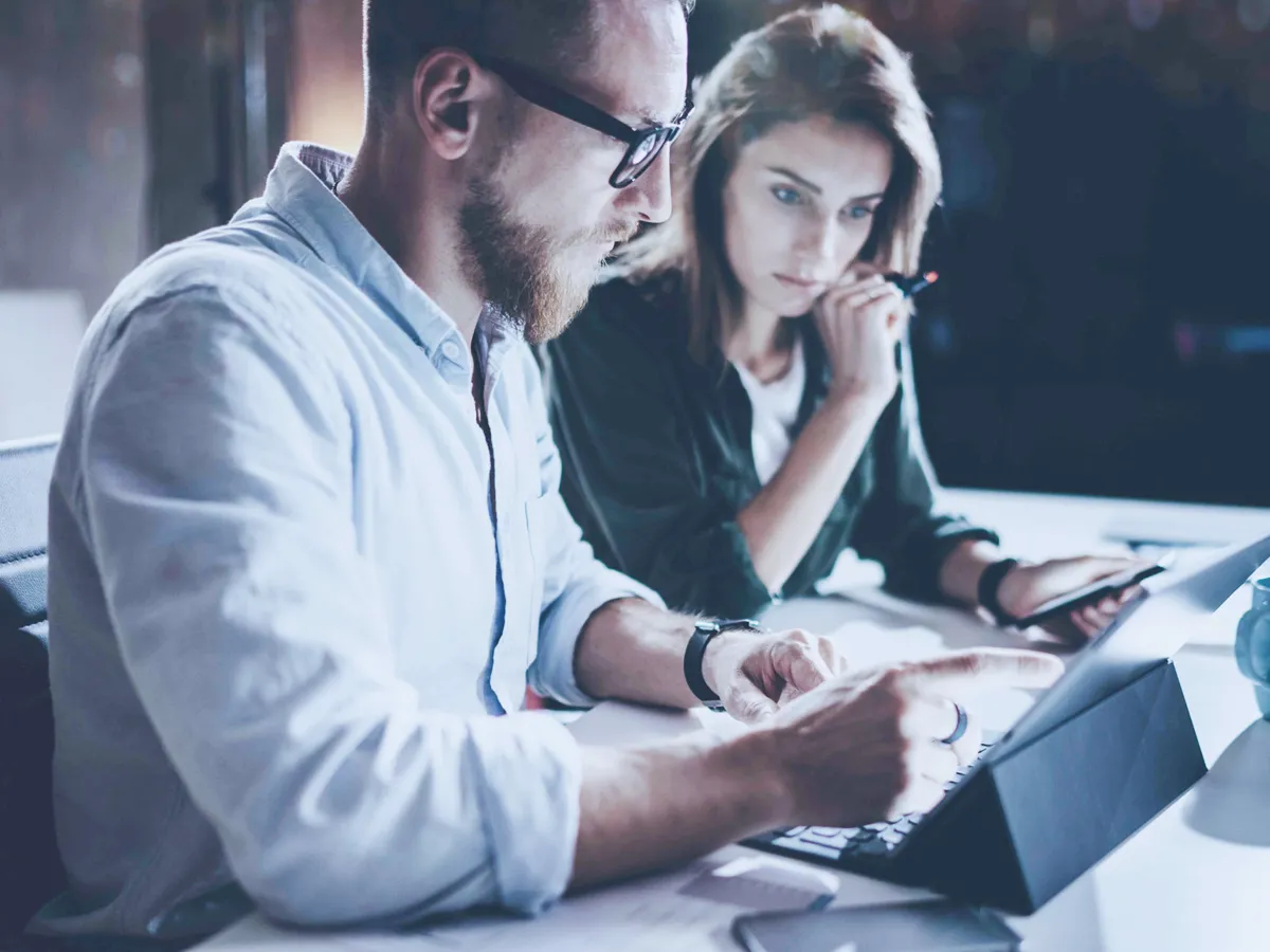 Man and woman looking and pointing at a tablet