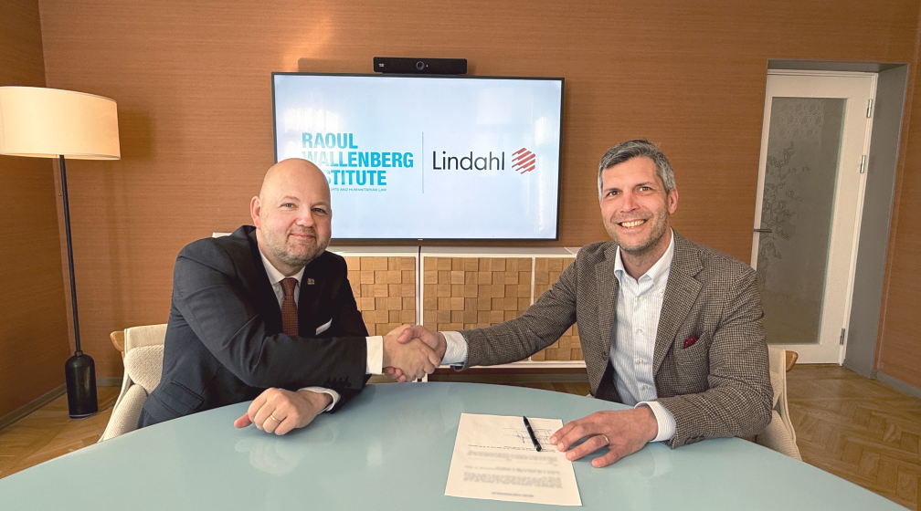 Two smiling men signing a contract shaking hands