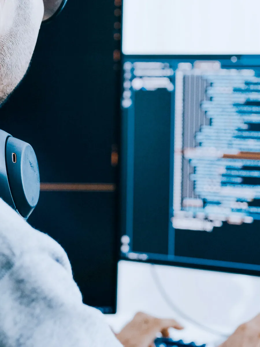 Man sitting at the computer with headphones around his neck