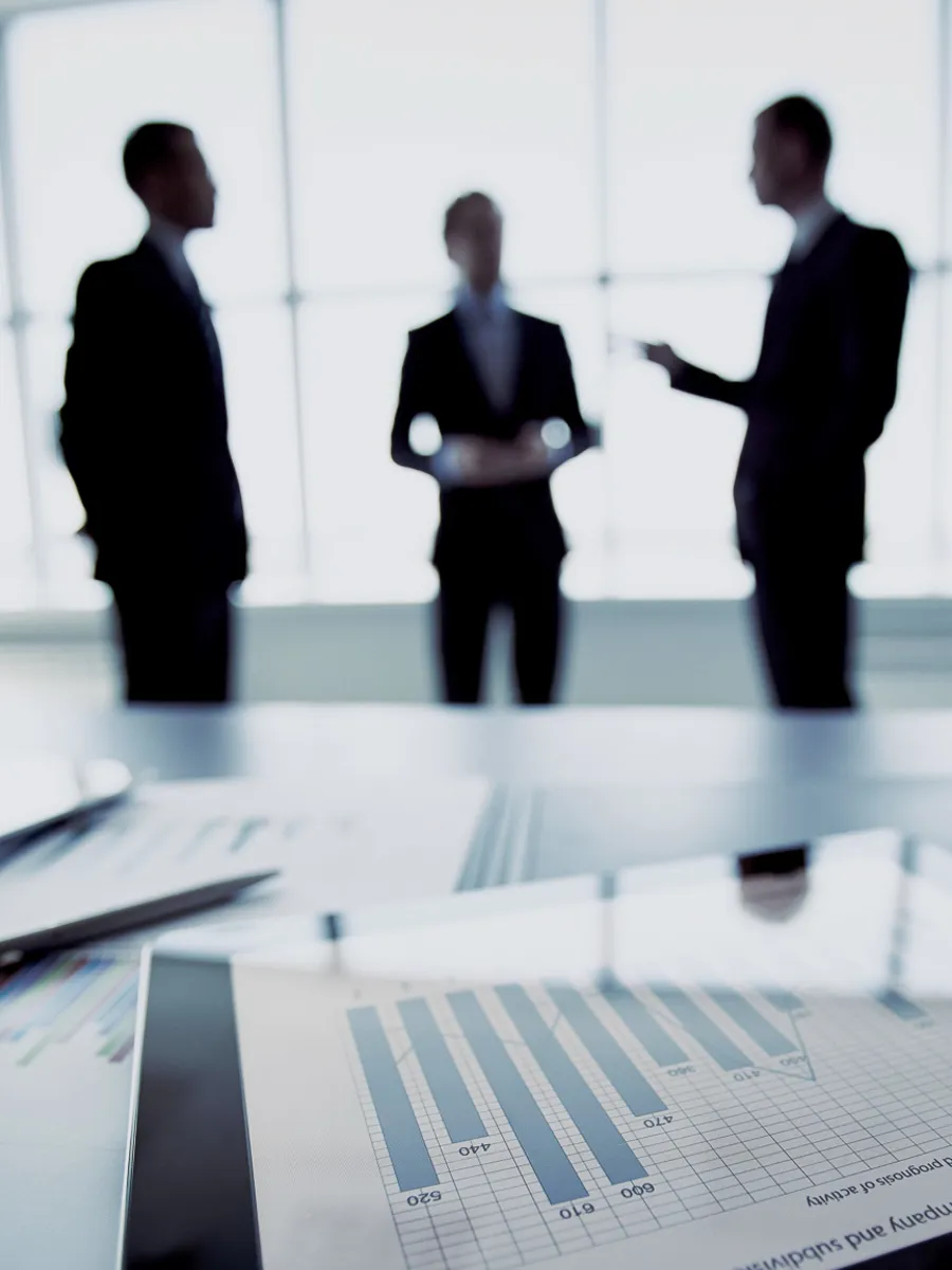 Skrivbord och tre affärsmän som diskuterar något